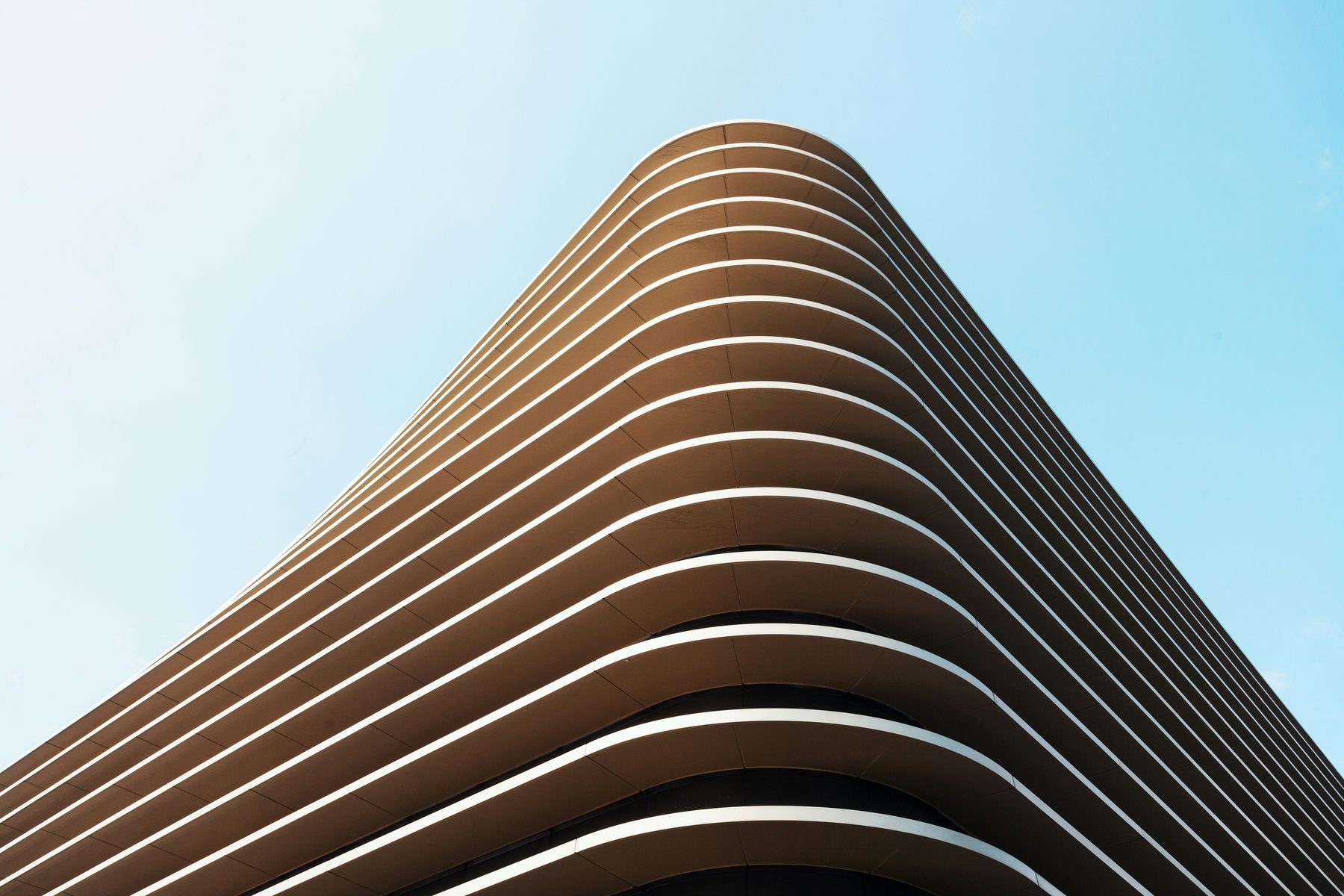 Curved bronze-clad building facade against a clear sky